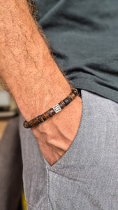 Close-up of a person wearing a beaded amber bracelet with a visible Vytis.