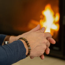 Load image into Gallery viewer, Men
 wearing a baltic amber bracelet with a warm fire in the background