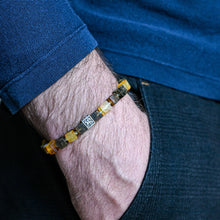 Load image into Gallery viewer, Close-up of a person wearing a beaded bracelet on their wrist with a blue shirt and dark jeans.
