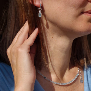 Close-up of a woman wearing silver earrings and a necklace.