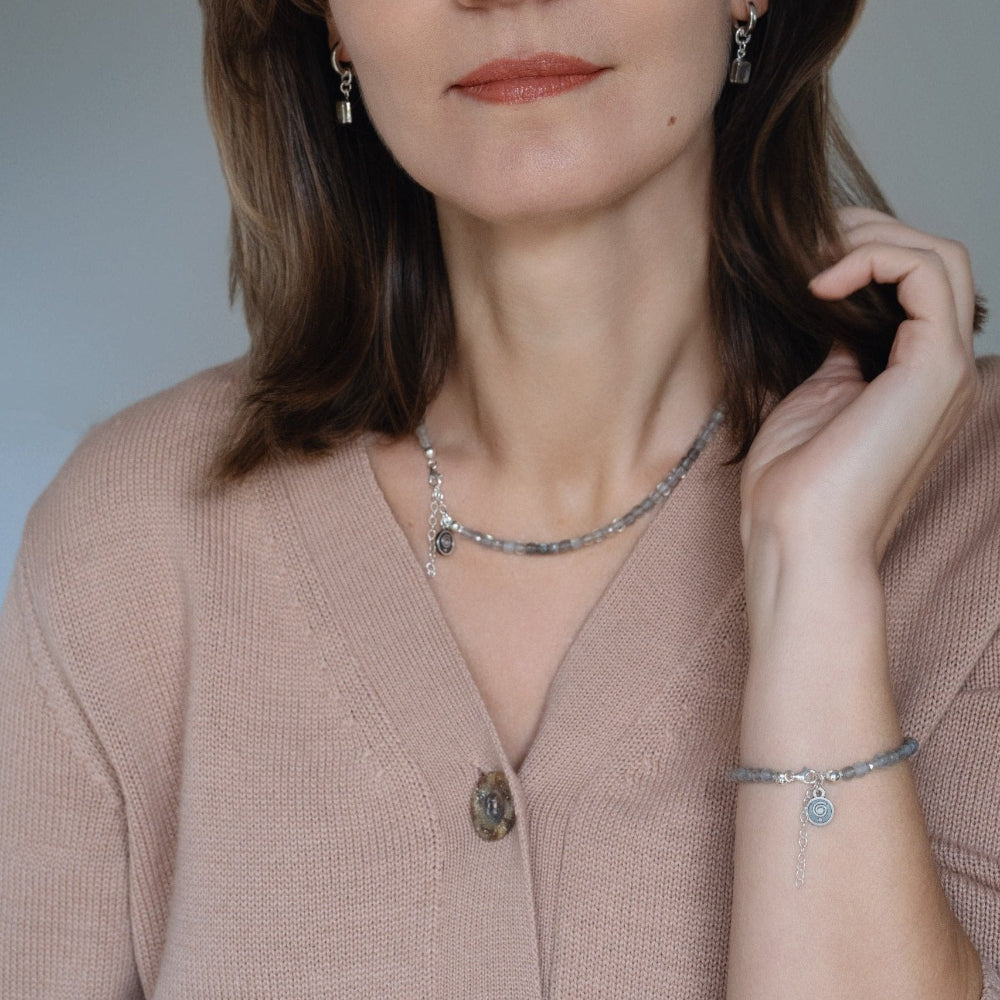 Woman wearing a necklace and bracelet with a neutral background